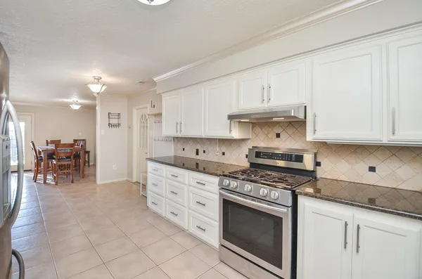 a kitchen with granite countertop a stove a sink and a refrigerator