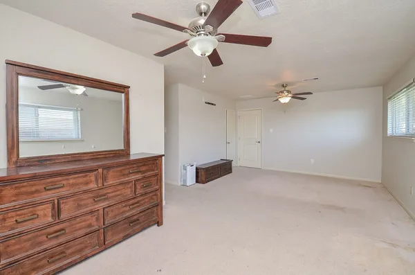 an empty room with fan and wooden floor
