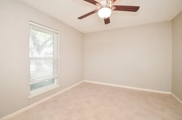 an empty room with a window and a fan