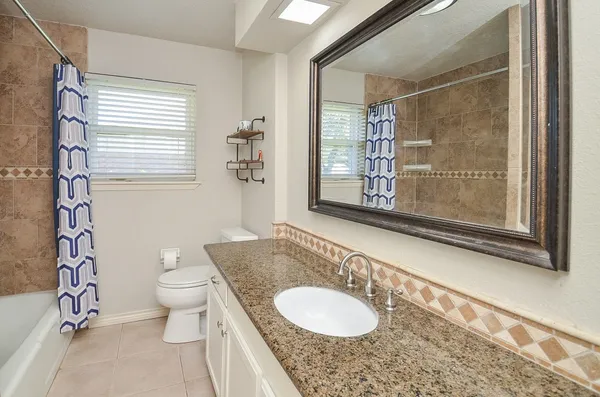 a bathroom with a granite countertop sink mirror vanity and toilet