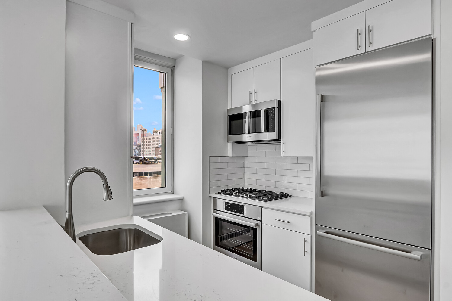 635 West 42nd Street, Unit 7A Manhattan, NY 10036 - Photo 17 of 28 a kitchen with white cabinets and stainless steel appliances
