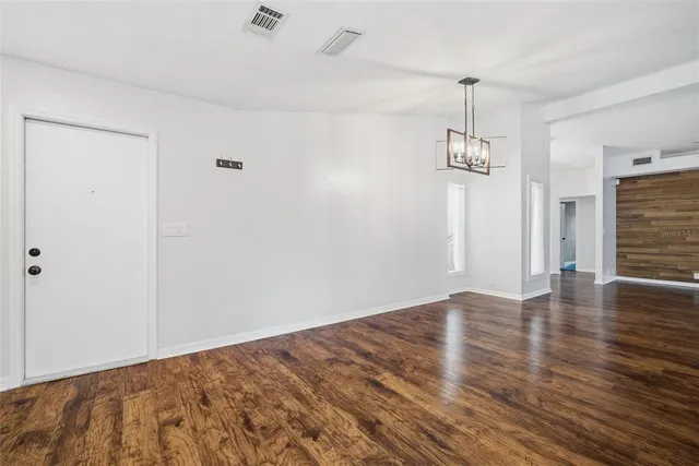 an empty room with wooden floor and ceiling fan
