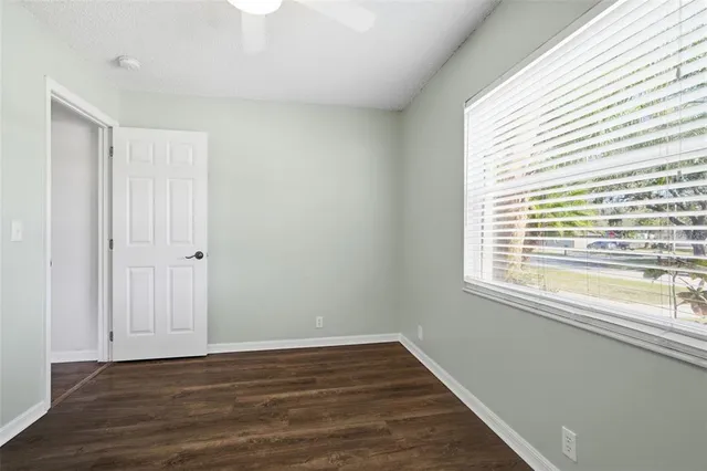 a view of an empty room with wooden floor and a window
