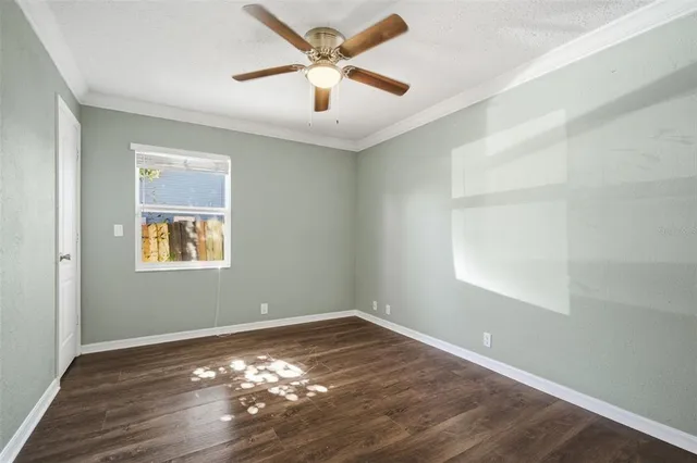 an empty room with wooden floor fan and windows