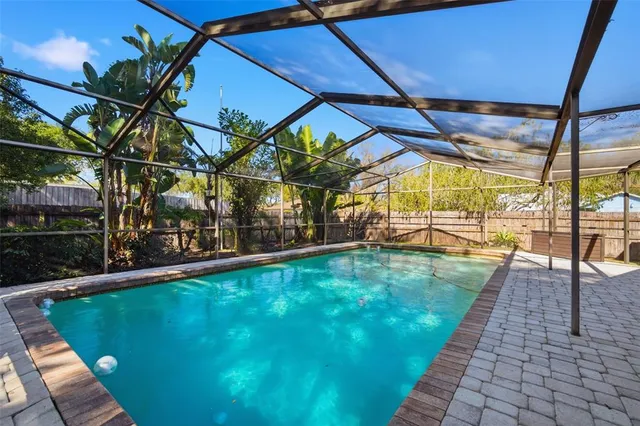an aerial view of a house with a yard swimming pool and large trees
