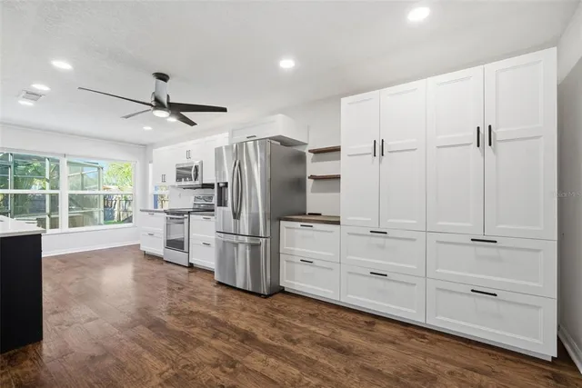 a living room with stainless steel appliances kitchen island hard wood floors and fireplace