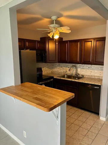 a kitchen with stainless steel appliances kitchen island granite countertop wooden cabinets a refrigerator and a sink