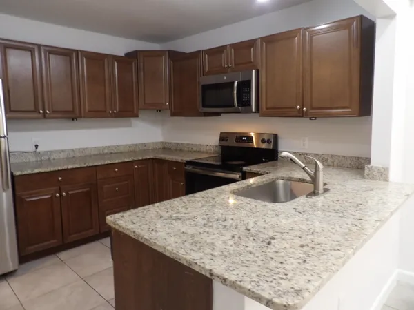 a kitchen with stainless steel appliances granite countertop a sink a stove microwave and cabinets