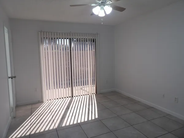 an empty room with floor to ceiling window and chandelier fan