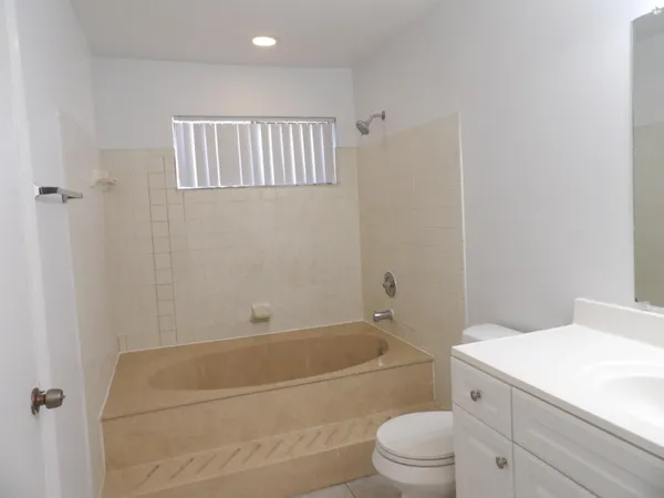 a bathroom with a granite countertop sink a toilet and bathtub