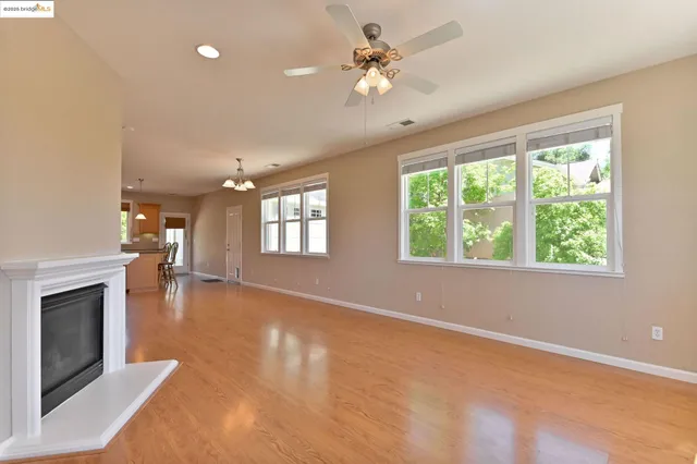 an empty room with windows fireplace and a kitchen view