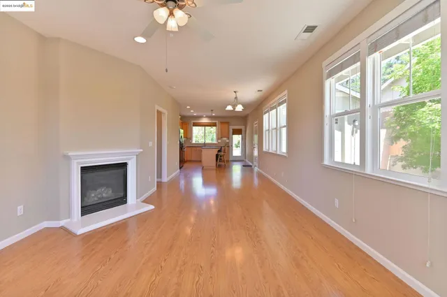 a view of an empty room with wooden floor fireplace and a window