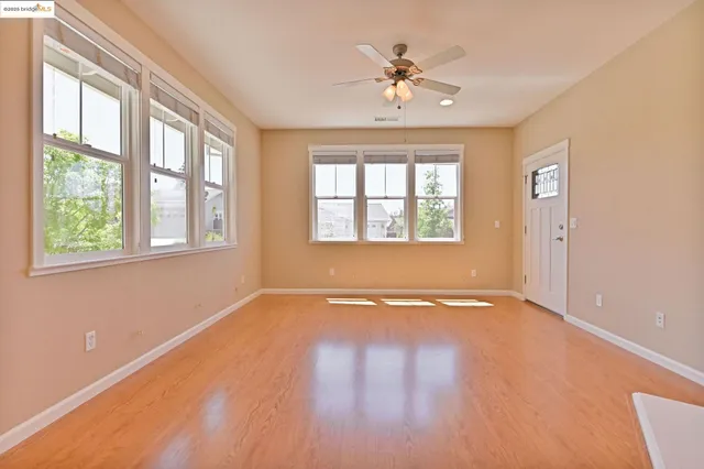 a view of an empty room with a window and wooden floor