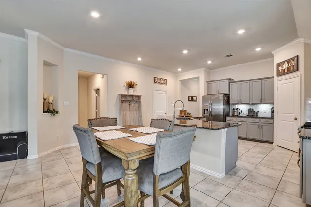 a kitchen with a dining table chairs and refrigerator