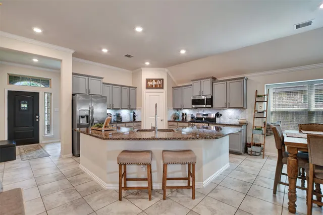 a kitchen with stainless steel appliances granite countertop a stove a sink a dining table and chairs