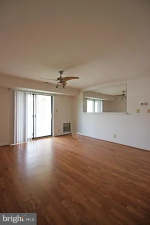 a view of empty room with wooden floor and fan