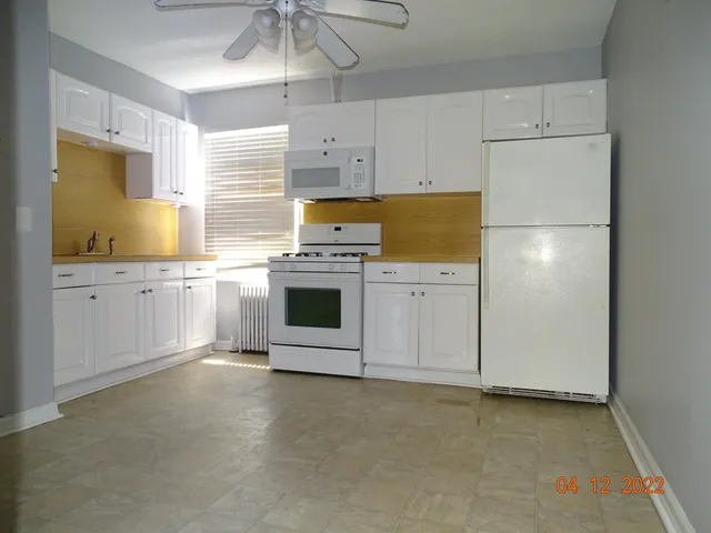 a kitchen with stainless steel appliances a stove top oven a refrigerator a sink and white cabinets