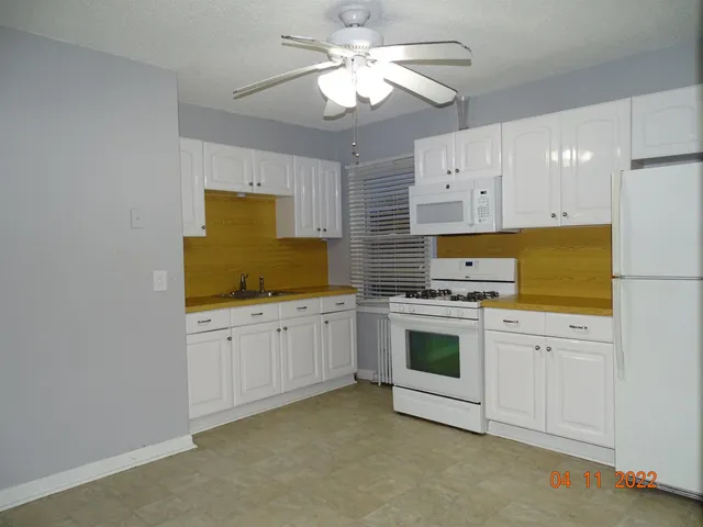 a kitchen with granite countertop white cabinets and white appliances