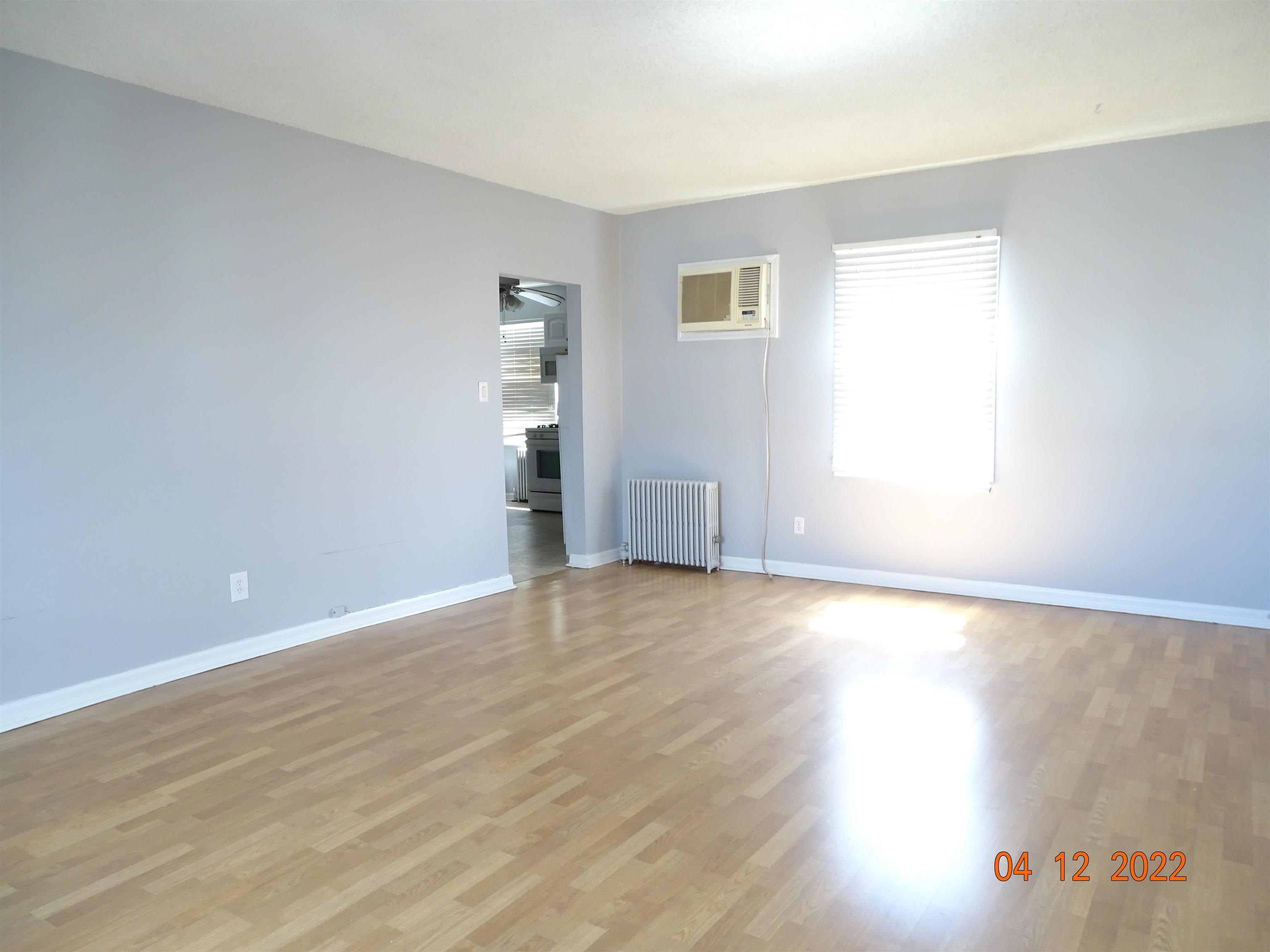 124 West 8th Street, Unit 2 Bayonne, NJ 07002 - Photo 5 of 19 a view of an empty room with wooden floor and a window