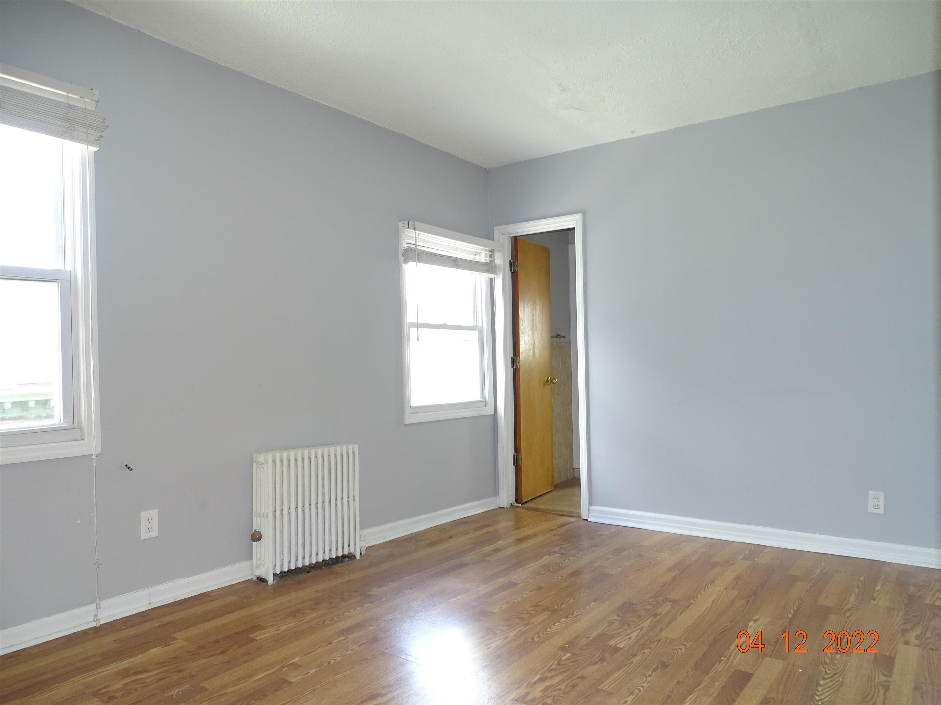124 West 8th Street, Unit 2 Bayonne, NJ 07002 - Photo 9 of 19 an empty room with wooden floor and windows