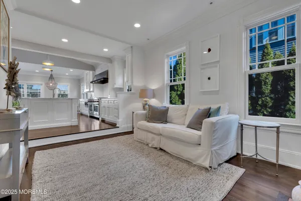a living room with furniture dining table a flat screen tv and a chandelier