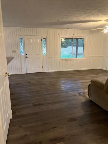 a view of an empty room with window and wooden floor