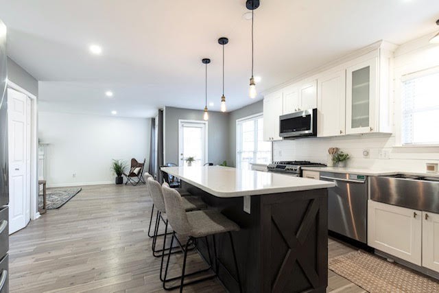 a kitchen with stainless steel appliances a table chairs refrigerator and microwave