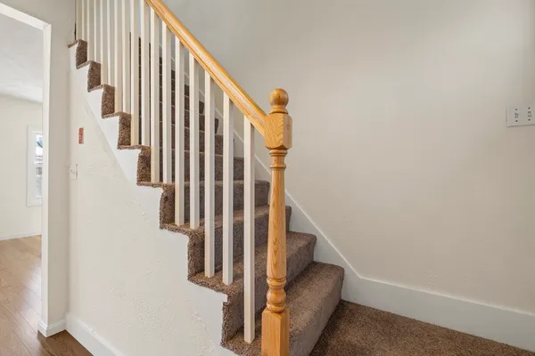 a view of staircase with lots of frames on wall and a window