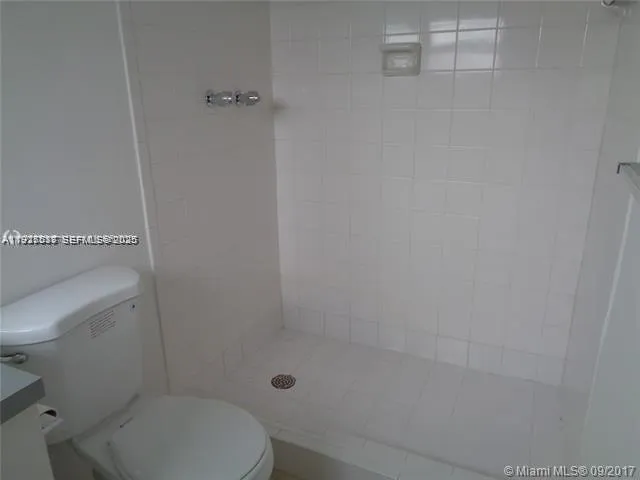 a white toilet sitting next to a shower