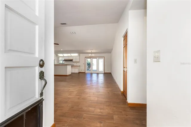 a view of a hallway with wooden floor windows and a kitchen