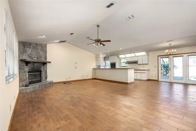 an empty room with wooden floor kitchen view and a window