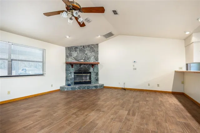 a view of empty room with wooden floor and ceiling fan