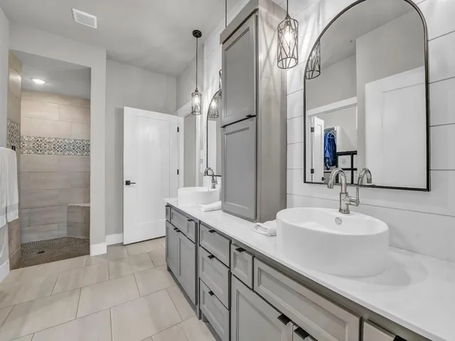 a bathroom with a double vanity sink a shower and a mirror