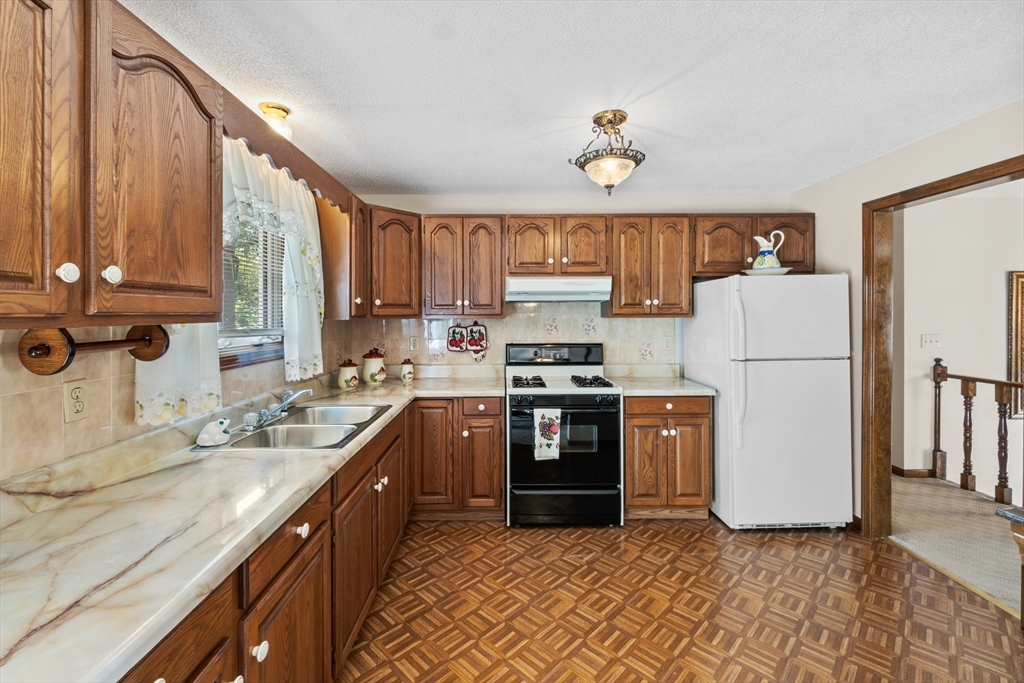 403 Aetna Street Fall River, MA 02721 - Photo 11 of 42 a kitchen with a refrigerator a stove top oven and a sink