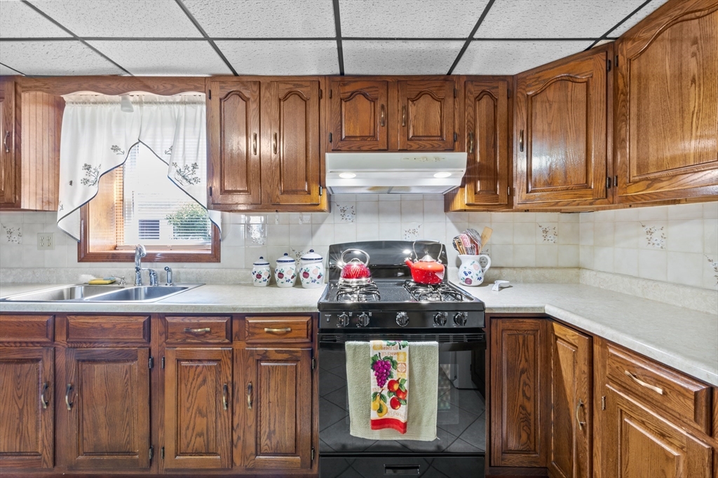 403 Aetna Street Fall River, MA 02721 - Photo 33 of 42 a kitchen with granite countertop a sink a stove and a wooden cabinets