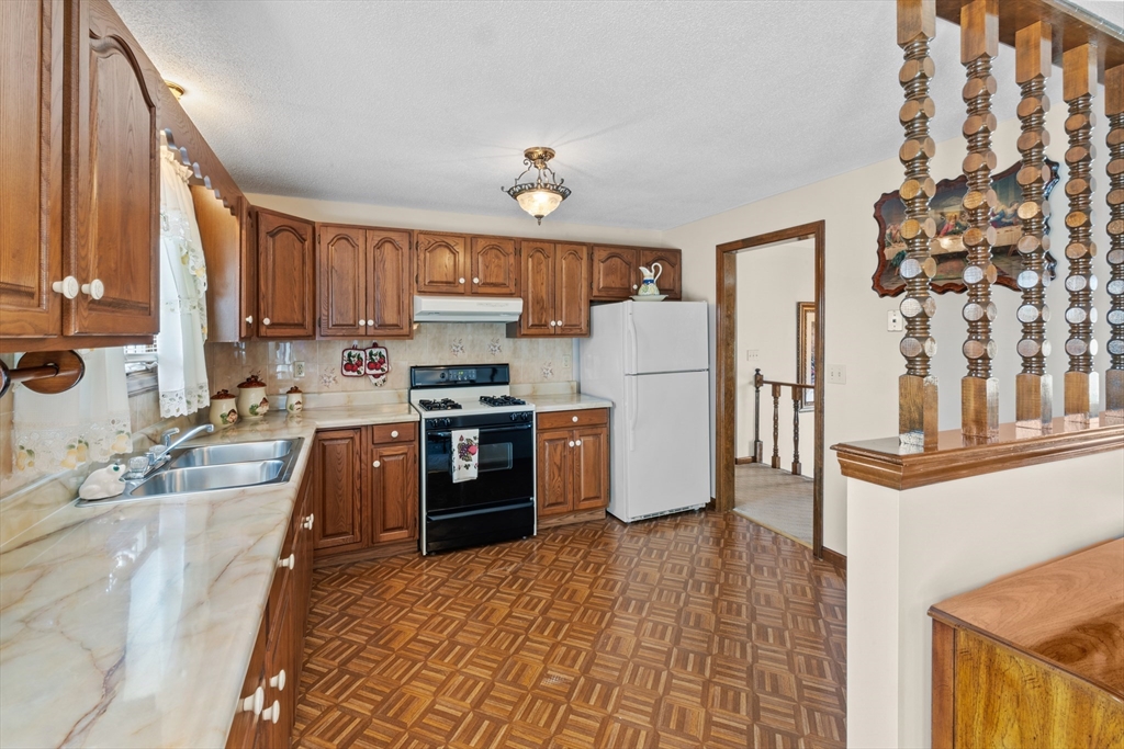 403 Aetna Street Fall River, MA 02721 - Photo 10 of 42 a kitchen with granite countertop a refrigerator a stove top oven and a sink