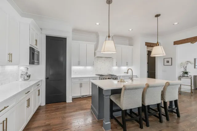 a open kitchen with stainless steel appliances granite countertop a stove a sink a island with a dining table and chairs