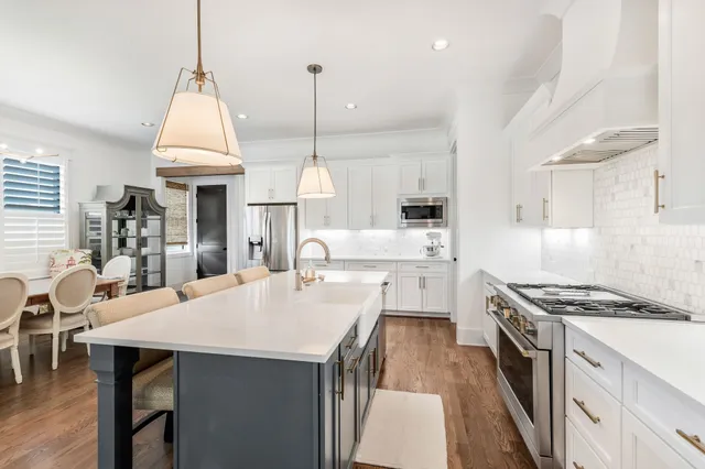 a kitchen with stainless steel appliances a stove a sink a kitchen island with wooden floor and cabinets