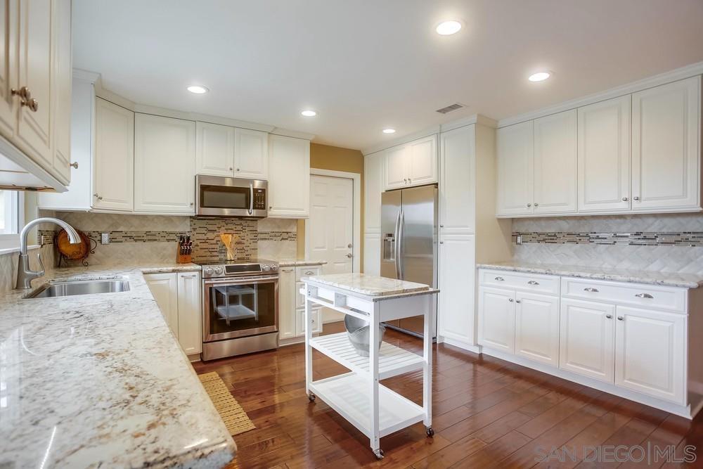 a kitchen with granite countertop a stove a sink and a refrigerator