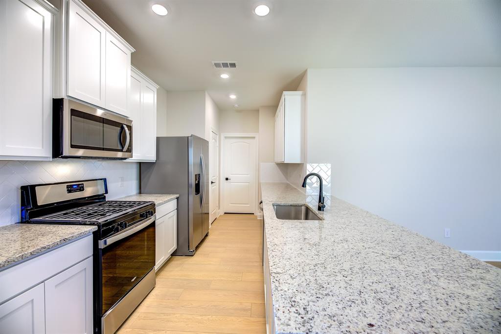 1330 Windemere Way Princeton, TX 75407 - Photo 6 of 25 a kitchen with stainless steel appliances granite countertop a sink stove microwave and refrigerator