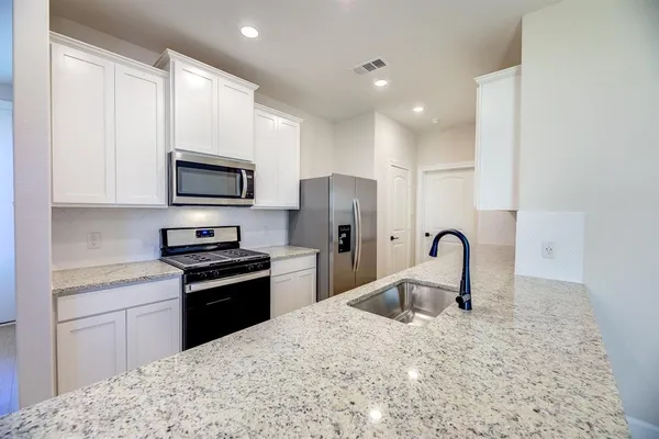 a kitchen with stainless steel appliances kitchen island a refrigerator sink and cabinets