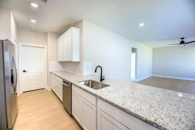 a kitchen with stainless steel appliances granite countertop a sink and a refrigerator