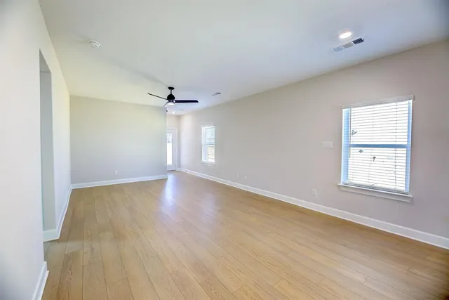 an empty room with wooden floor and windows