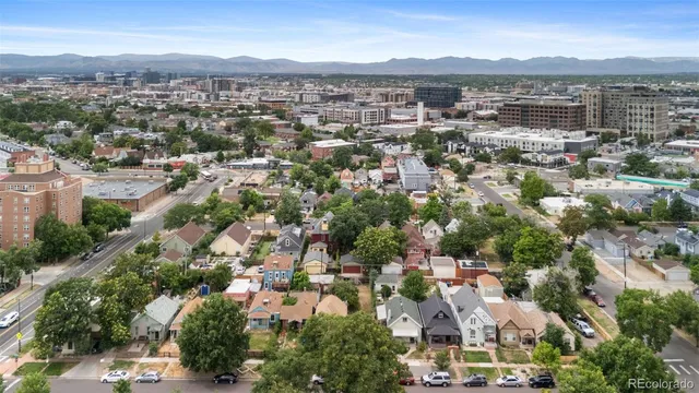 an aerial view of a city with lots of residential buildings and mountain view in back