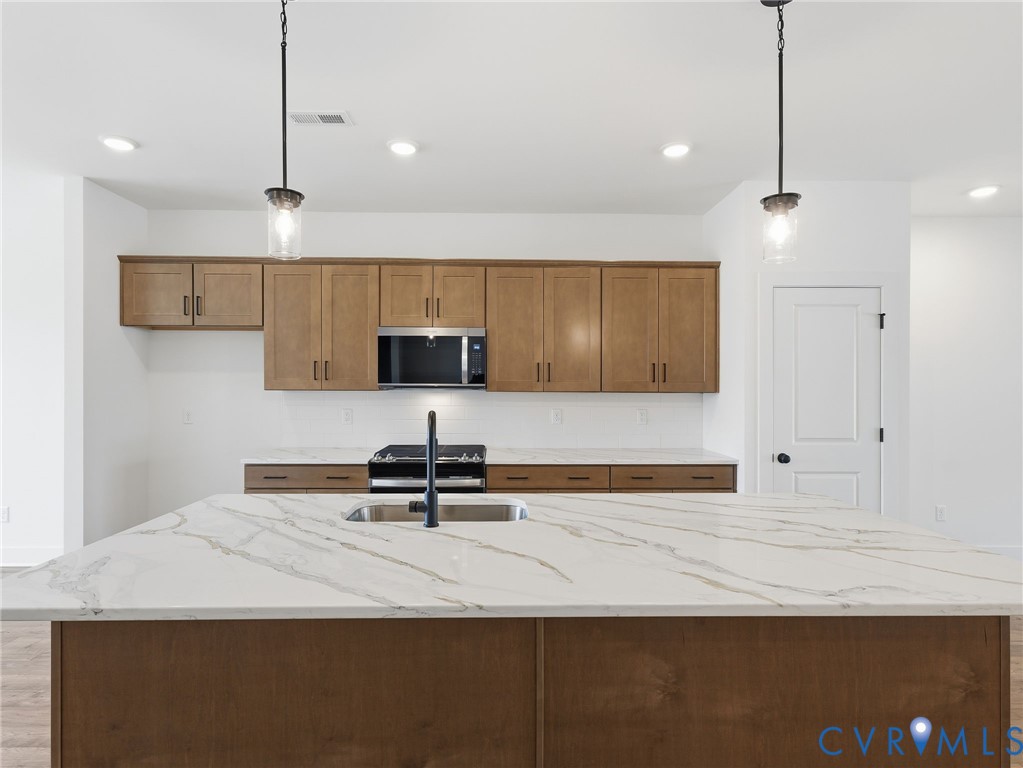 12026 Flowering Lavender Loop Henrico, VA 23233 - Photo 14 of 42 a kitchen with kitchen island a counter top a stove a sink and a window