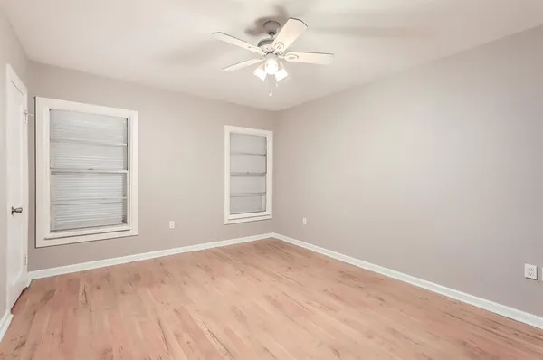 an empty room with chandelier fan and windows