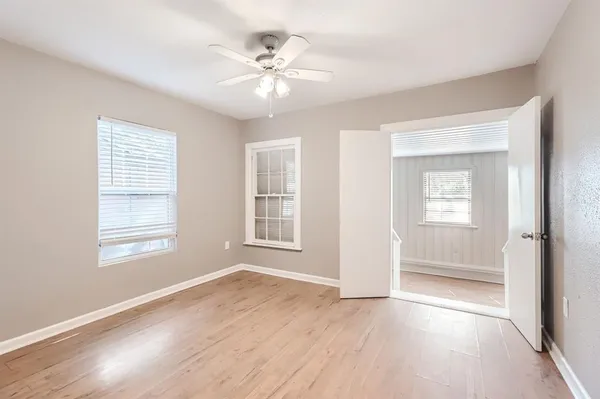 a view of an empty room with a window and wooden floor