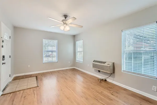 a view of an empty room with a window and wooden floor