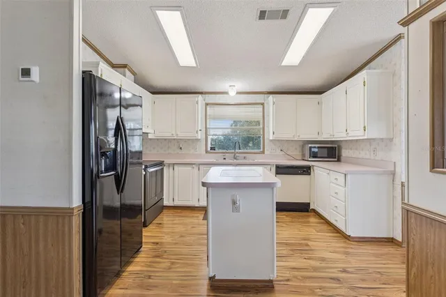 a kitchen with white cabinets appliances and a window