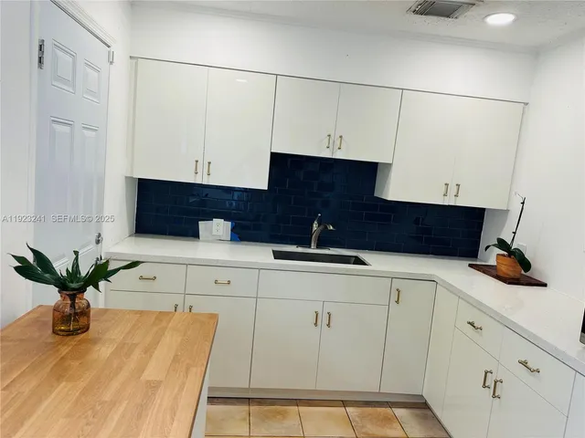 a kitchen with stainless steel appliances kitchen island granite countertop a refrigerator a sink and white cabinets